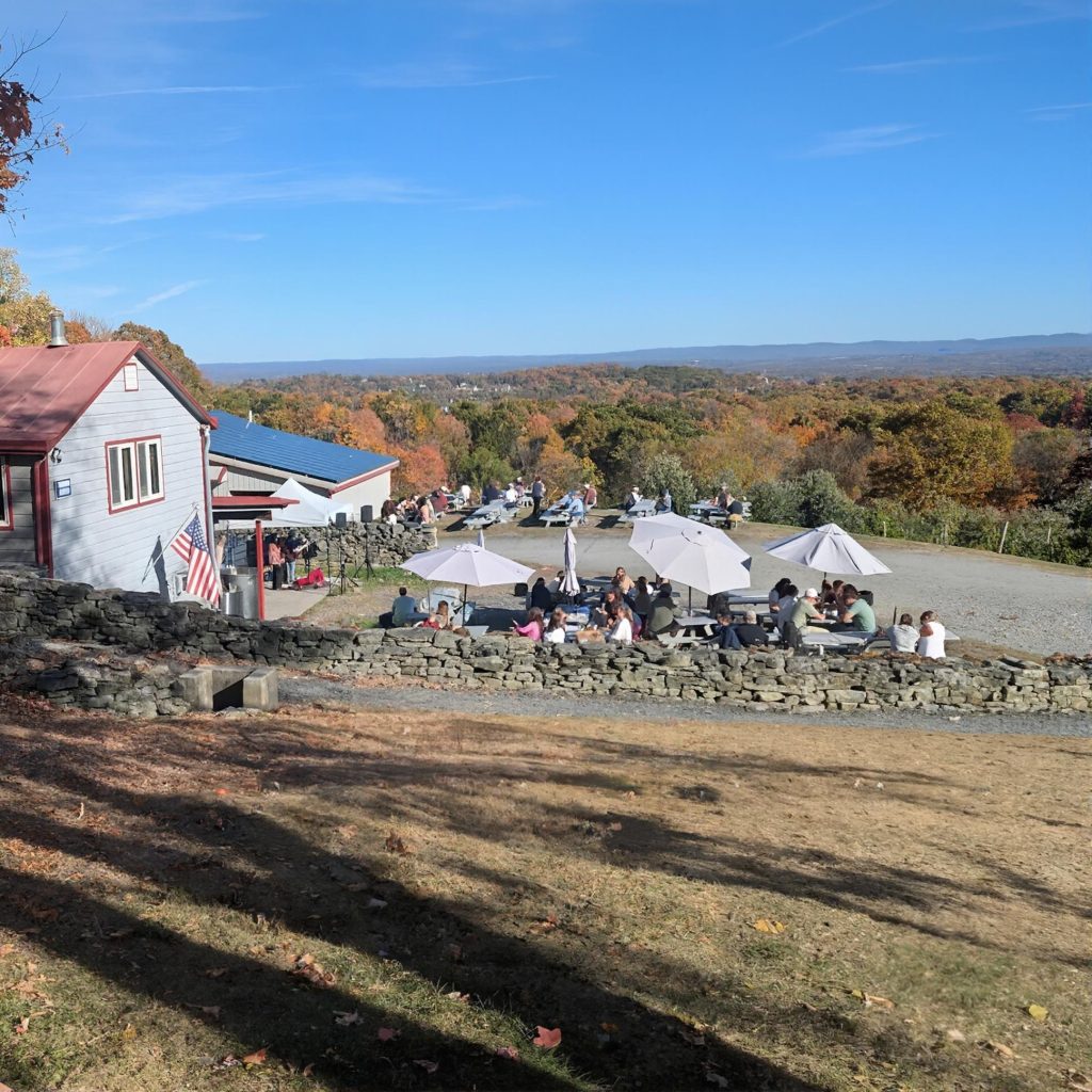 Outdoor picnic area with tables and umbrellas at Quartz Rock Vineyard in the Hudson Valley during a chauffeured wine tasting tour from Westchester County.